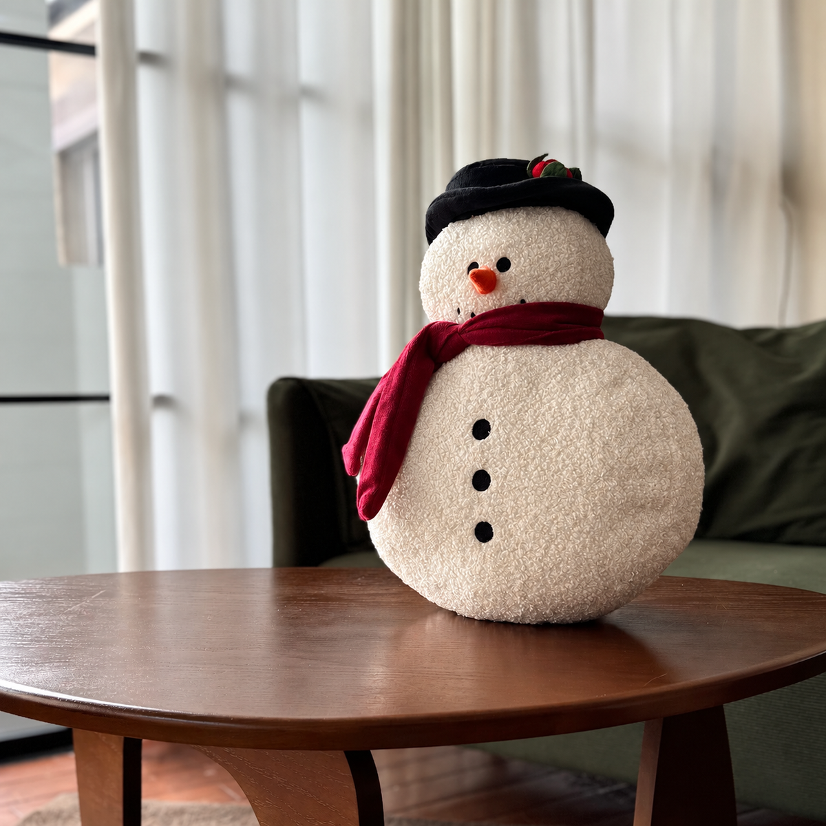 White snowman Christmas throw pillow wearing a black hat and burgundy scarf on a wooden table