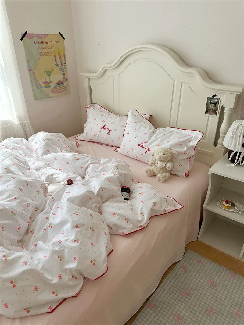 White bedspread with red floral patterns on a bed in a bedroom.