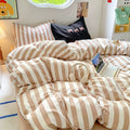 Cozy minimalist bed with beige duvet and pillowcases in pastel decor.