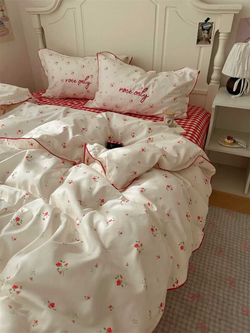 Bedding set with floral pattern and red trim on a bed in a bedroom.