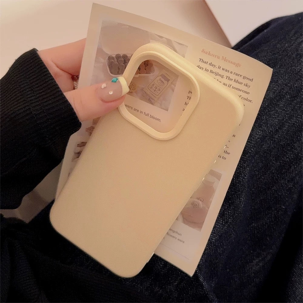 Beige phone case held by a hand on top of a magazine