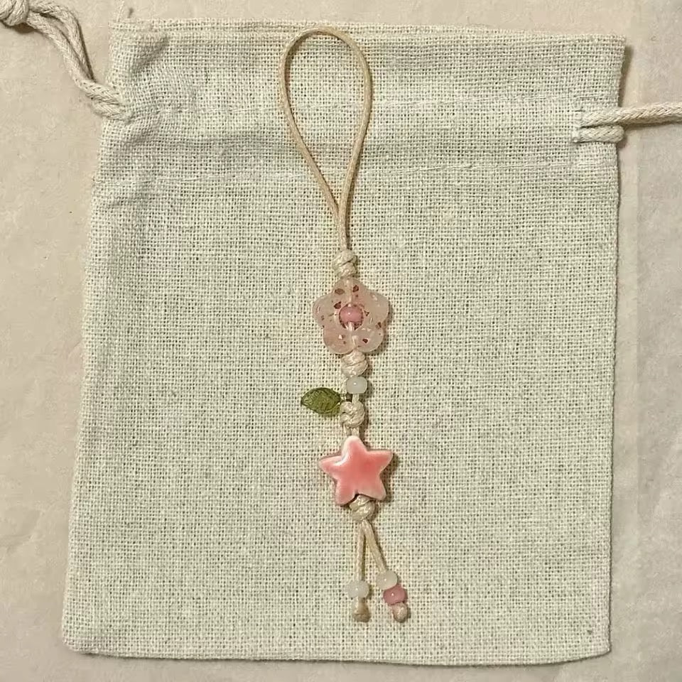 Decorative string with a pink star and floral elements on a textured beige background