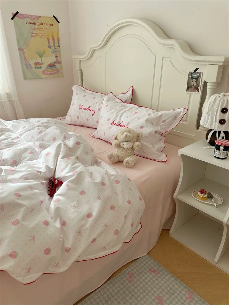 Bedroom with pink bedding and white headboard, featuring a teddy bear and decorative items.