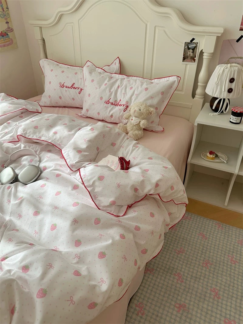 Bed with strawberry-themed bedding and pillows in a bedroom setting.