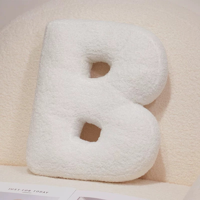 White letter 'B' pillow on a light pink background