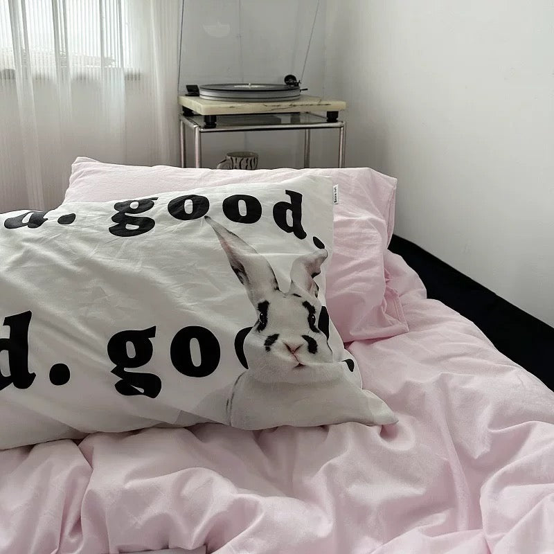 Minimalist pink bedding set styled in a cozy modern bedroom with typography pillows.