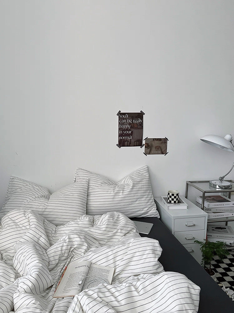 Bedroom with striped bedding and decorative items on a white wall.