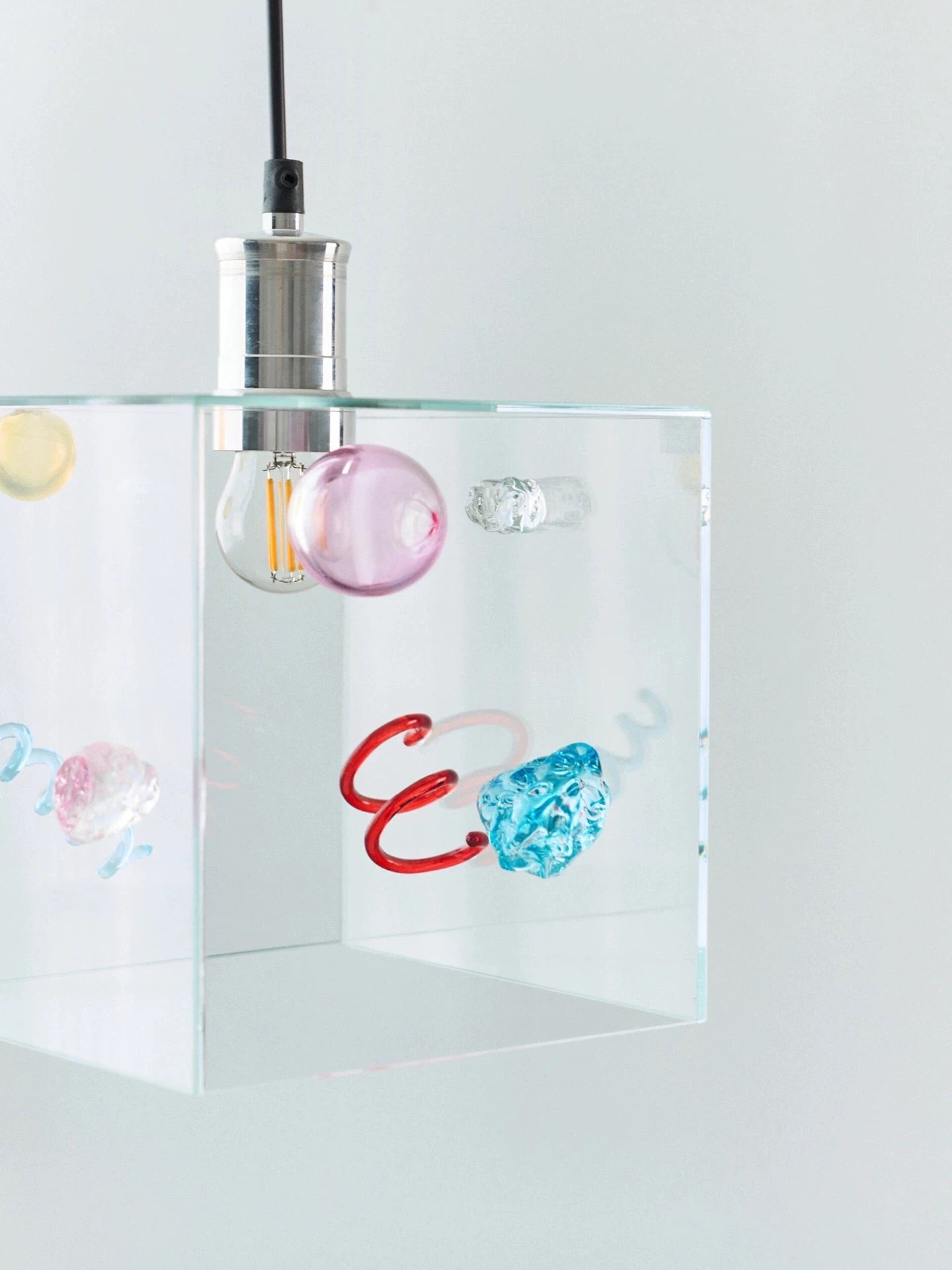 Modern pendant light with colorful glass shades on a white background