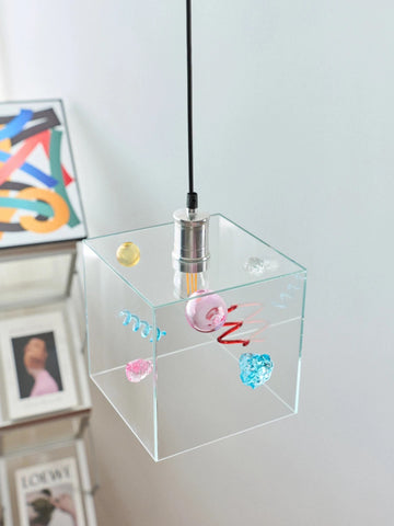 Clear glass pendant light with colorful decorations on a white wall background