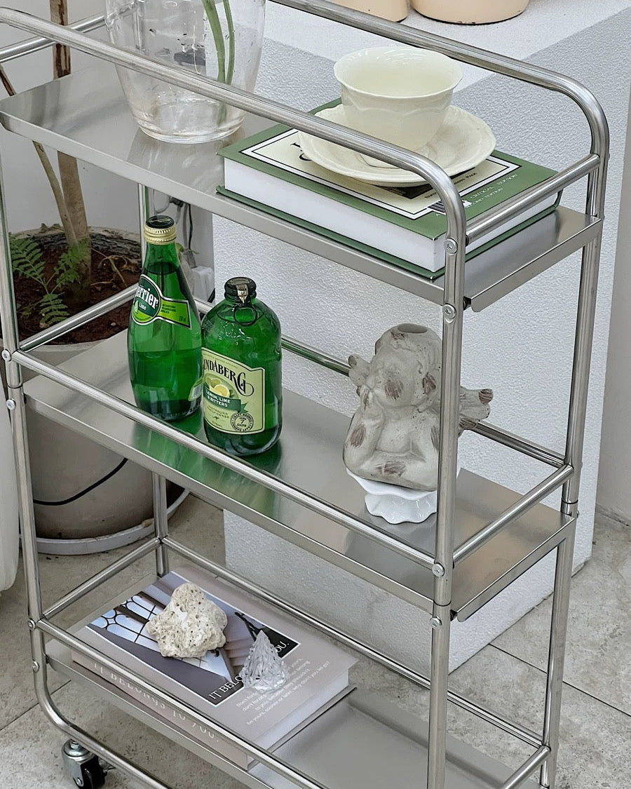 Stainless steel rolling storage cart with three shelves, wheels, and silver frame for home organization.