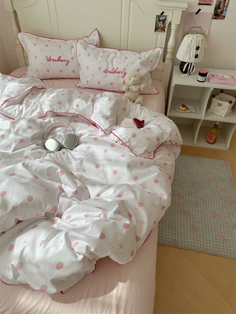 Bed with strawberry-themed bedding and pillows in a bedroom setting.