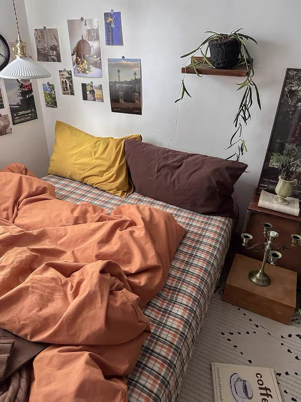 Bedroom with orange bedding and various decor items on the walls and shelves.