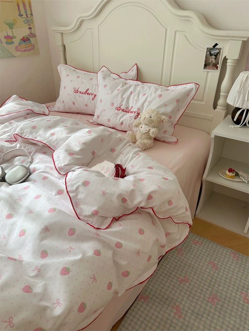 Bed with strawberry-themed bedding and pillows in a bedroom setting.