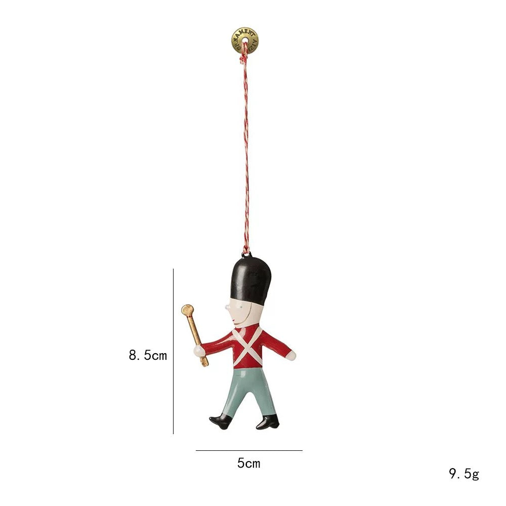 A toy soldier ornament has a red jacket, tall black hat, pale pants and a gold colored baton.