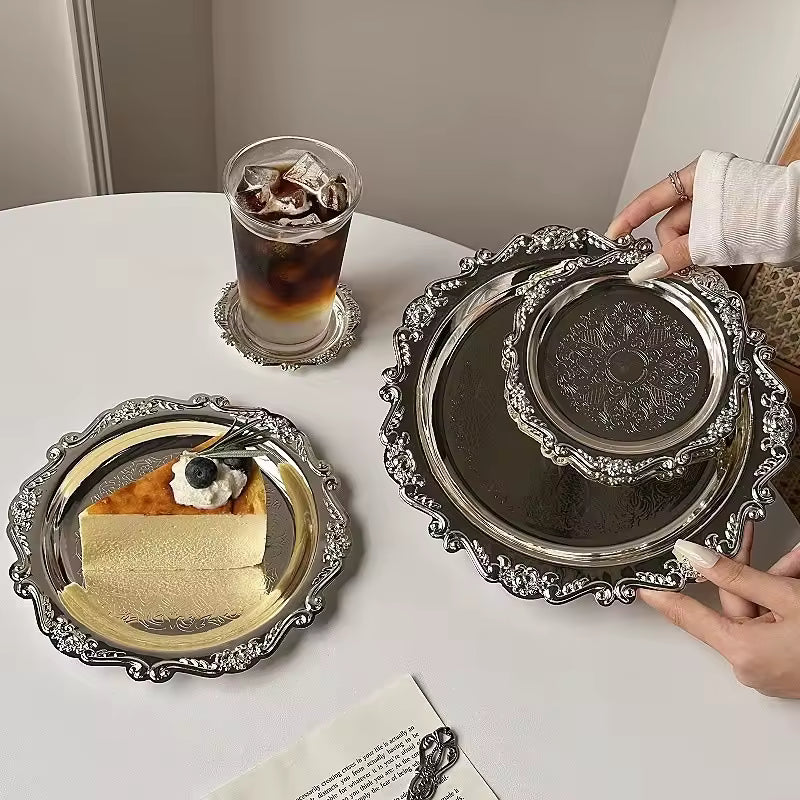 Decorative silver trays with a dessert and a drink on a table.