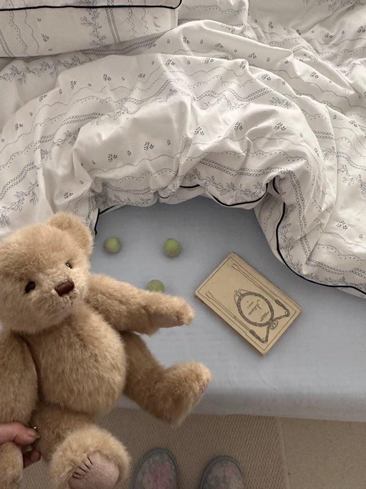 Teddy bear on a bed with a card and green balls
