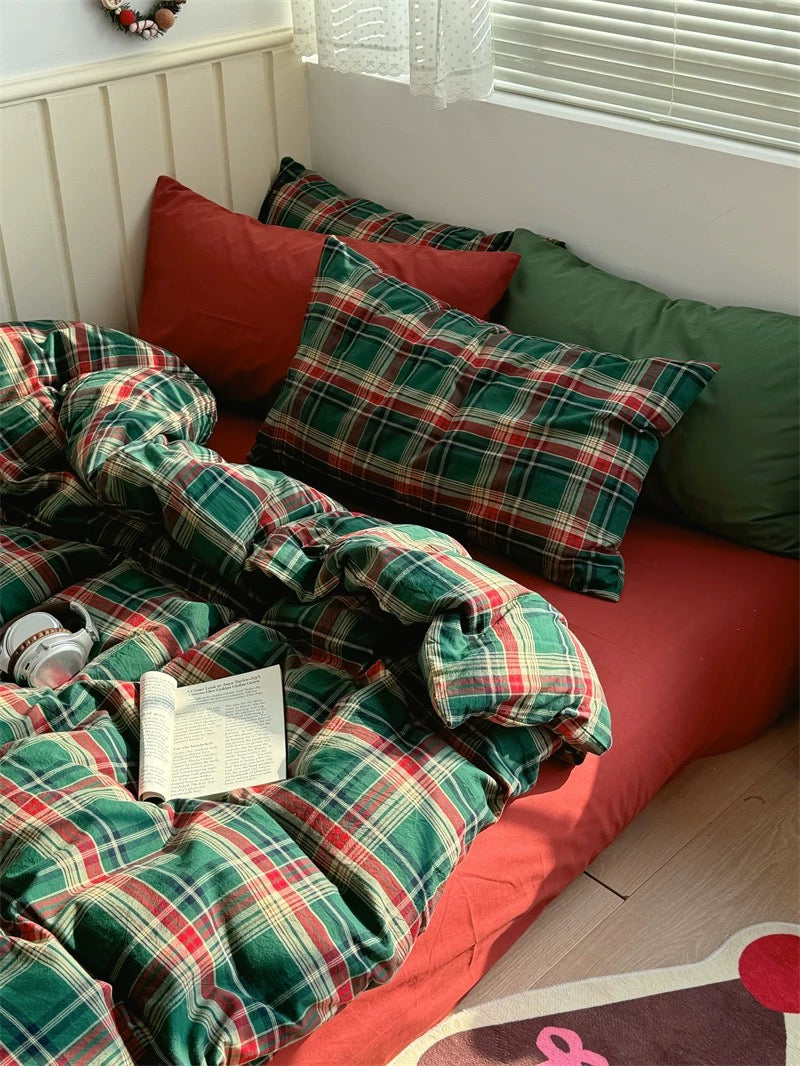 Plaid blanket and pillows on a bed with a book and candy canes.