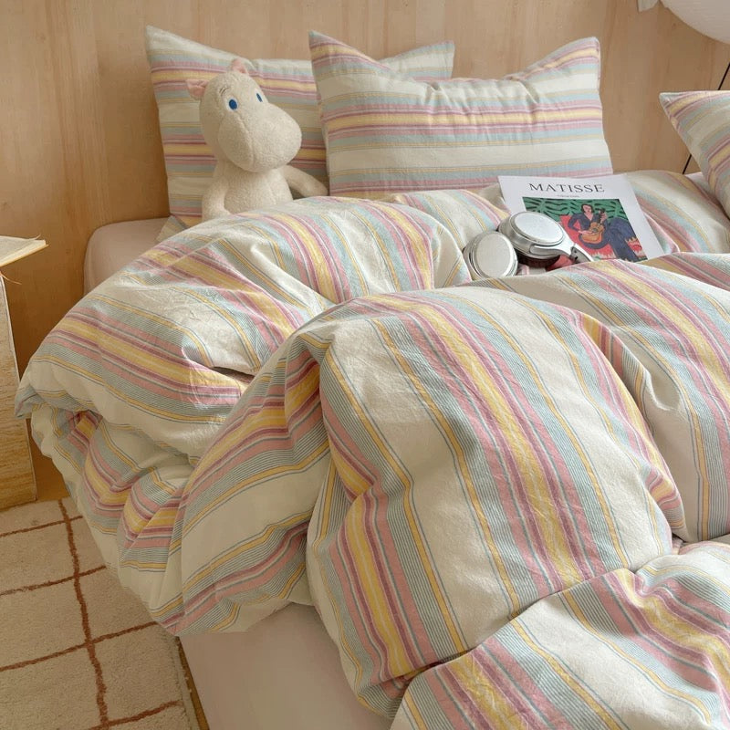 Bed with striped bedding, pillows, and a toy in a room.