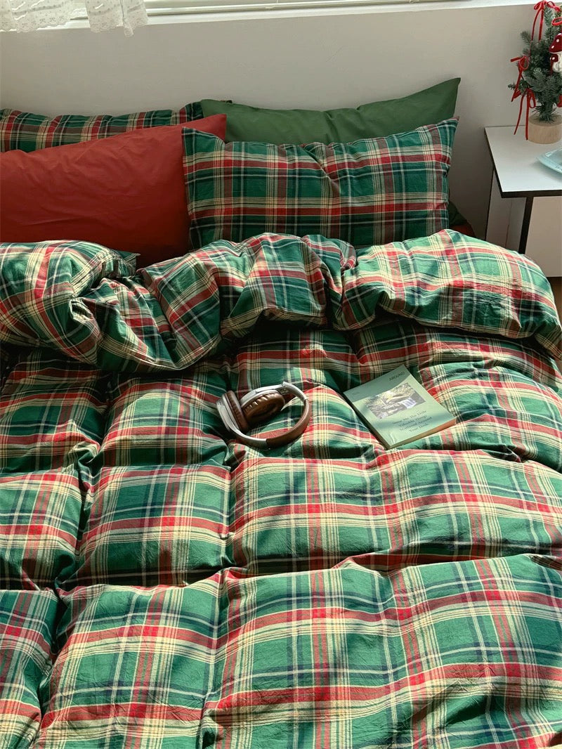 Plaid bedspread with red and green colors on a bed in a room.