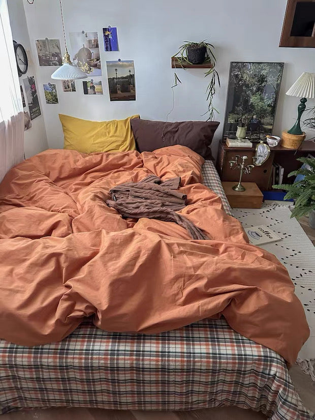 Bedroom with orange bedding and various decor items on the walls and shelves.