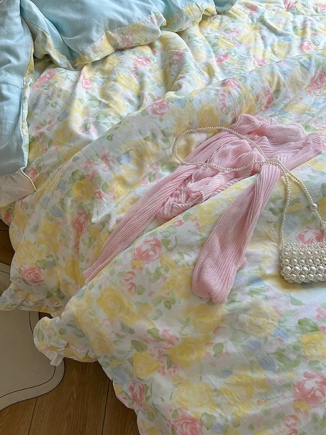 Watercolor rose duvet cover with a pink fabric accessory laid across the bed