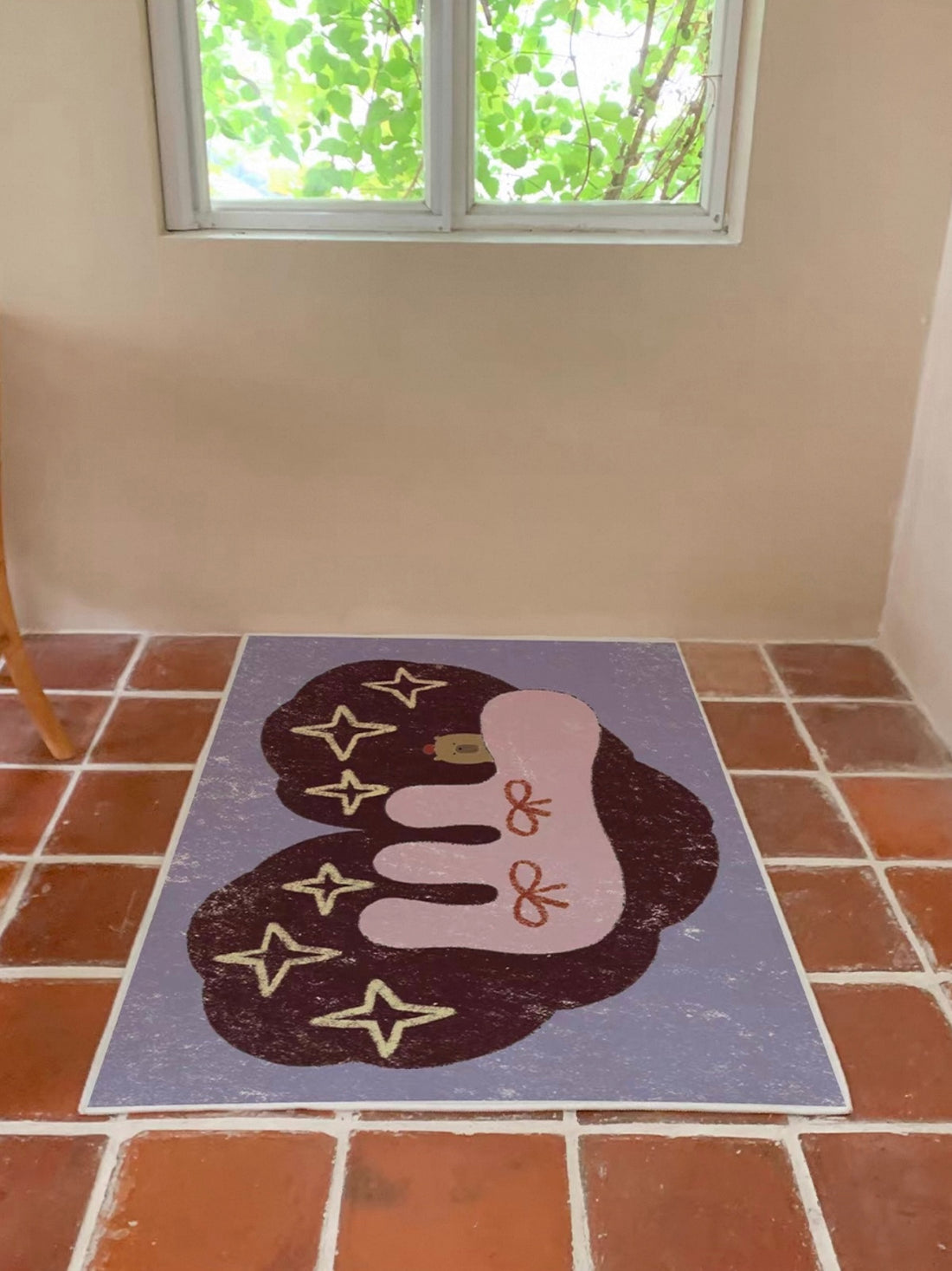 A Kawaii rug with a cream butterfly outline, flowers and a blue border lies beside open shelving.