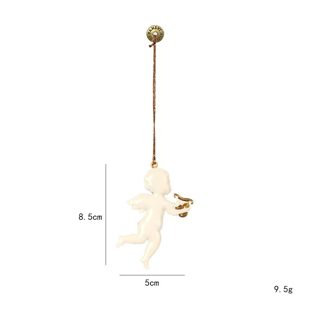 A white angel Christmas ornament carries a small gold lyre, with wings and one leg curved behind.