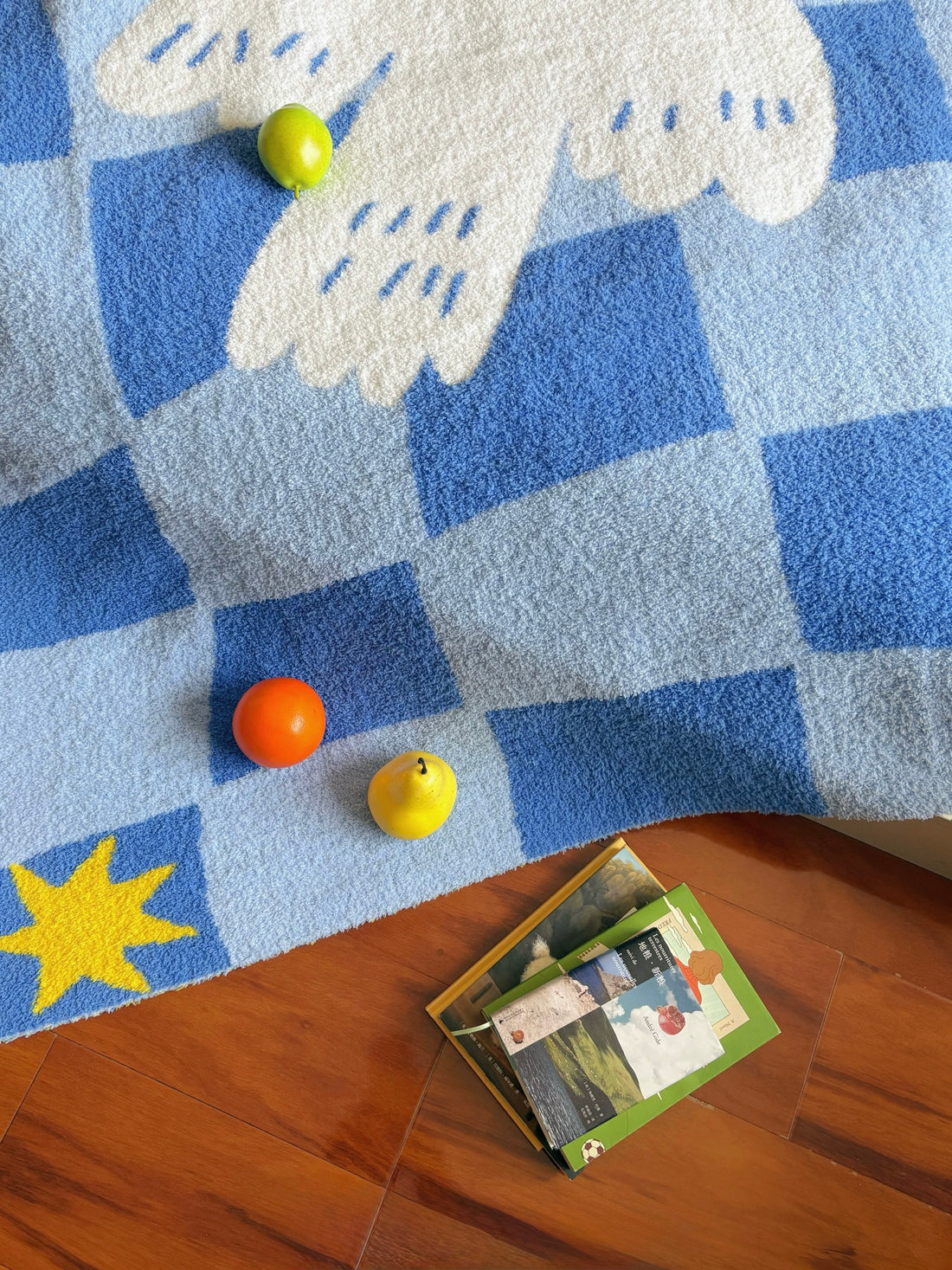 A blue and white checkered blanket with a white dove in the center and yellow star accents, draped over a bed in a bedroom setting.