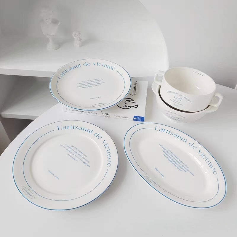 White ceramic dinnerware collection with blue French lettering including round oval plates and two bowls