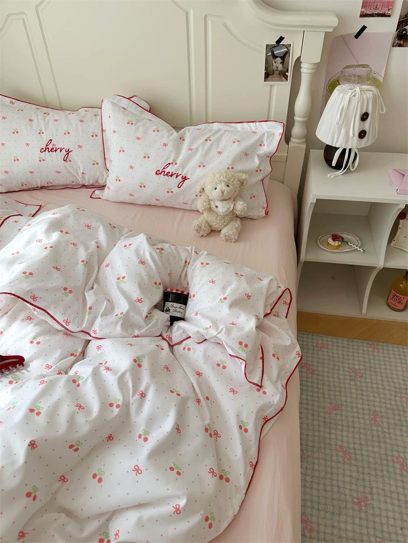 Bed with cherry-themed bedding and pillows in a bedroom setting.