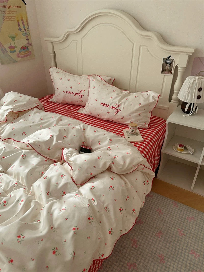 Bed with white and red checkered bedding and floral patterns in a bedroom setting.