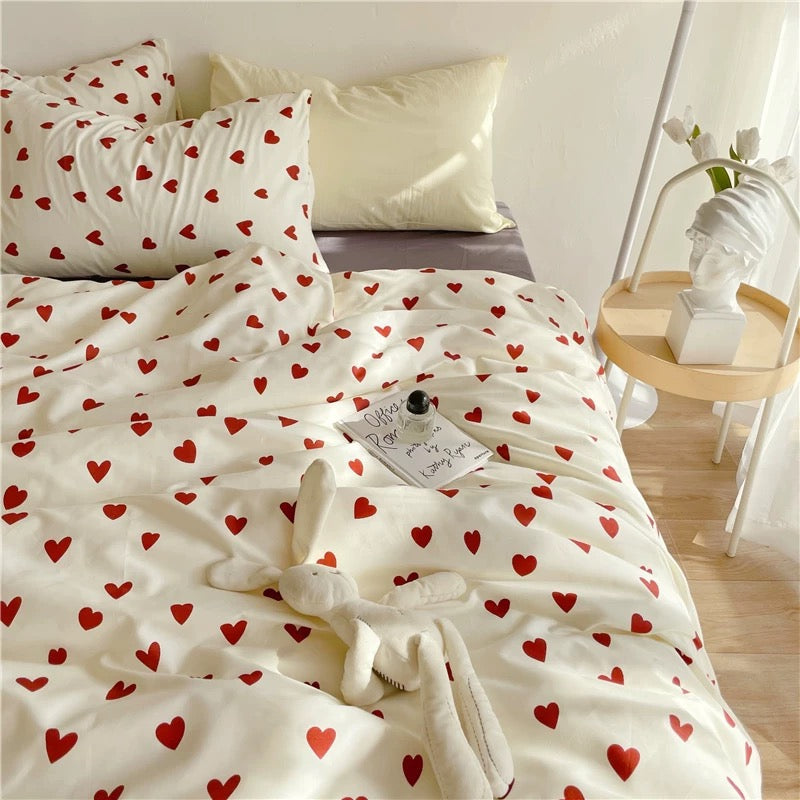 White heart duvet cover styled across a bed with coordinated red heart bedding