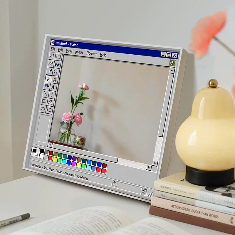 Digital art of a computer screen with a flower vase, lamp, and books on a desk.