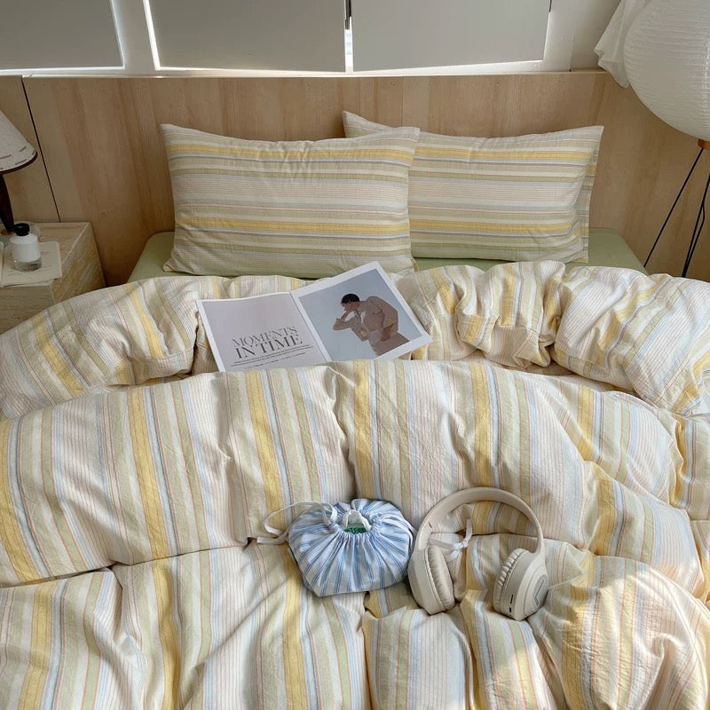 Bed with striped bedding and pillows in a bright room
